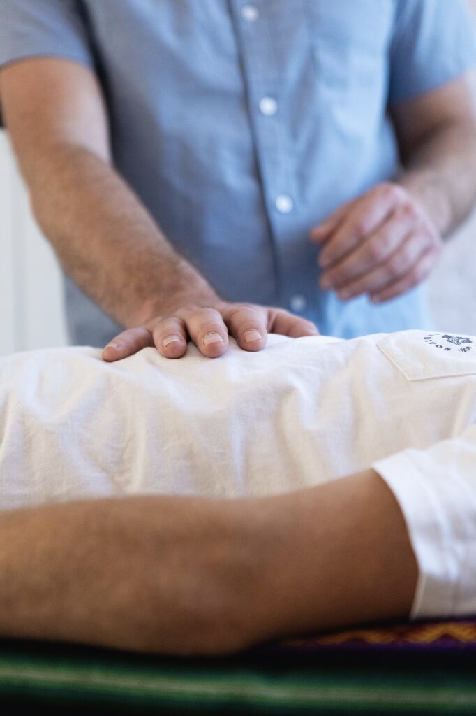 Therapist's hand pressing on a patient's back during a treatment or massage.