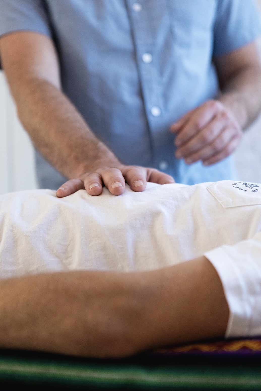 Therapist's hand pressing on a patient's back during a treatment or massage.